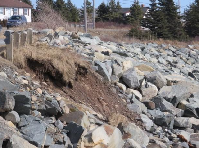Le français suit. A close-up image of the part of the coast along Shore Road, which shows a mix of rock armouring and eroding vegetation. Image en gros plan d'une partie de la côte le long de Shore Road, qui montre un mélange d'enrochement et de végétation en voie d'érosion.